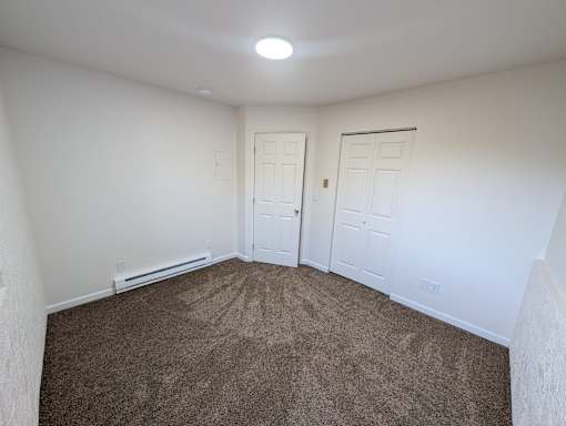 A room with carpeted floor and two doors.