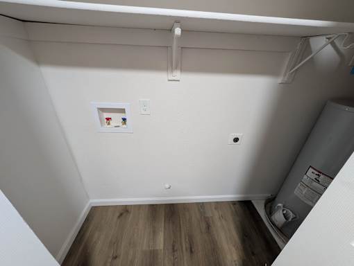 A small room with a white wall and a wood floor.
