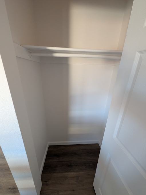 A white hallway with wood floors and white walls.