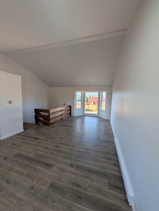 A room with wooden flooring and white walls.
