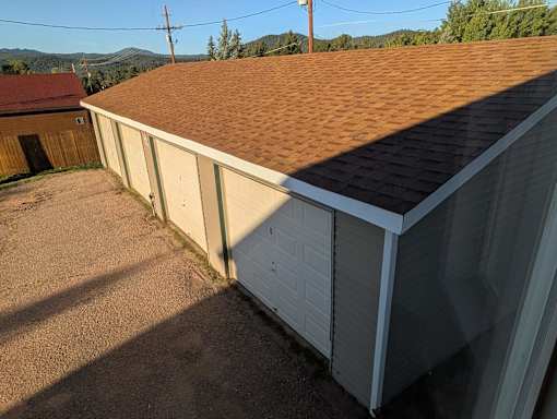 A brown shingled roof on a tan garage.