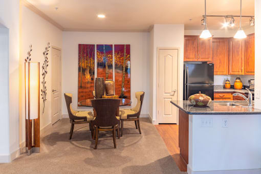 a kitchen and dining room with a table and chairs and a painting on the wall