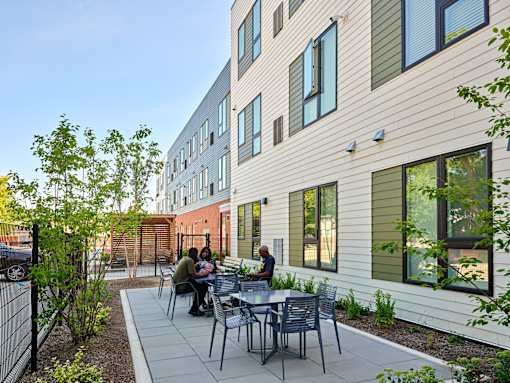 A group of people are sitting at a table outside of a building.