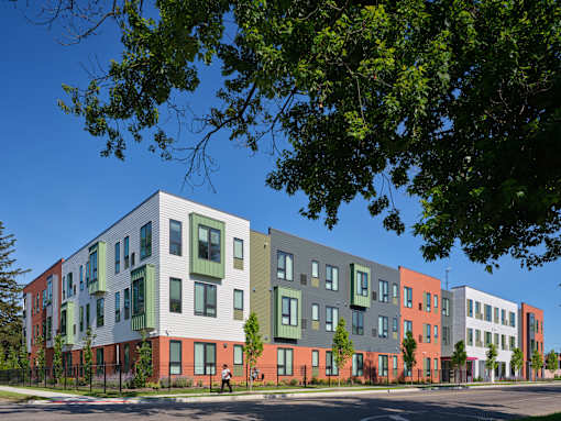 A row of modern townhouses with green trees in the foreground.