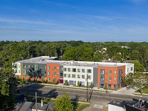 A multi-story building with a red and white facade is surrounded by trees.