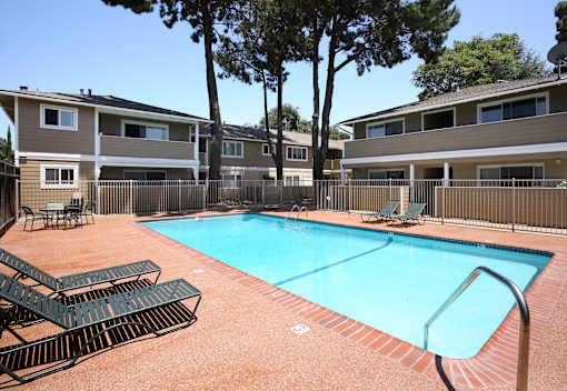 A swimming pool surrounded by lounge chairs and trees.