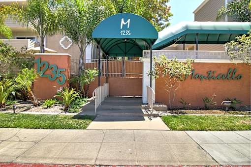The entrance to a building with a green awning and a sign