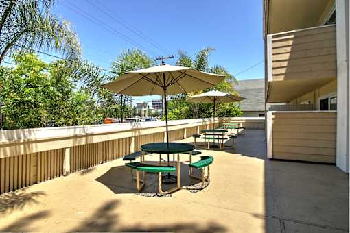 A sunny day at a patio with a green table and chairs.