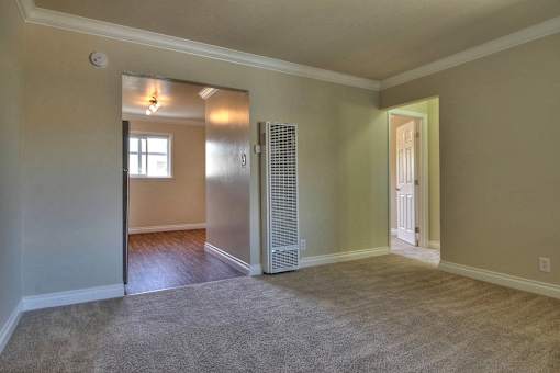 an empty living room with an open door to a bedroom