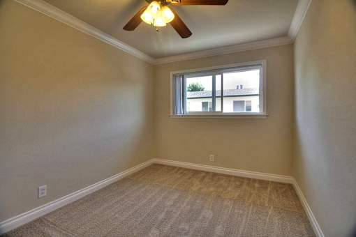 an empty bedroom with a window and a ceiling fan