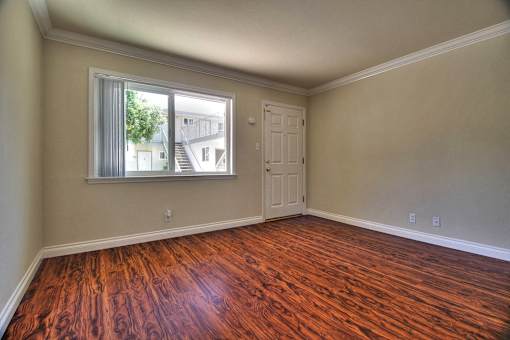 an empty living room with wooden floors and a window
