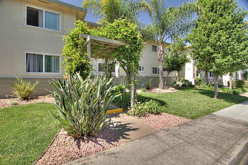a sidewalk in front of the building with a garden