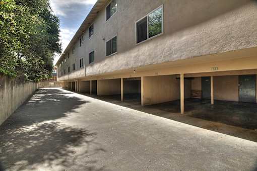 A long concrete walkway leads to a building with a row of windows.