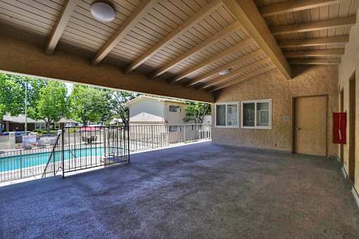 A covered patio area with a pool and a fence.