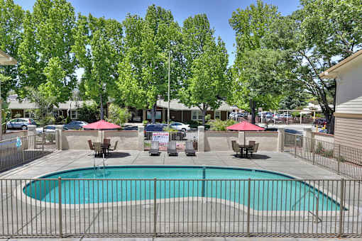 A pool surrounded by a fence with trees in the background.