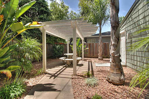 A patio with a white pergola and a bench.