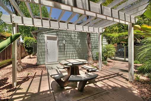 A patio with a table and chairs under a white pergola.