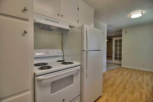 A kitchen with a stove and refrigerator built into the wall.