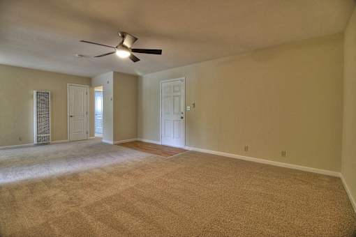 A room with a ceiling fan and carpeted floor.