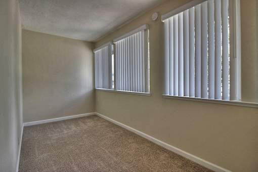 A room with a window covered by white blinds.