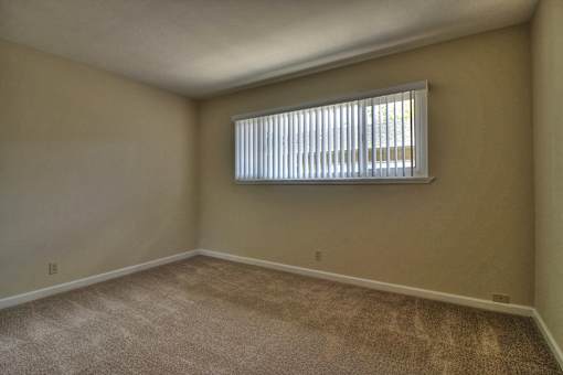 A room with a window covered by white blinds.
