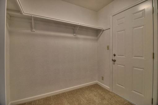 A white door is on the right side of a room with a carpeted floor.