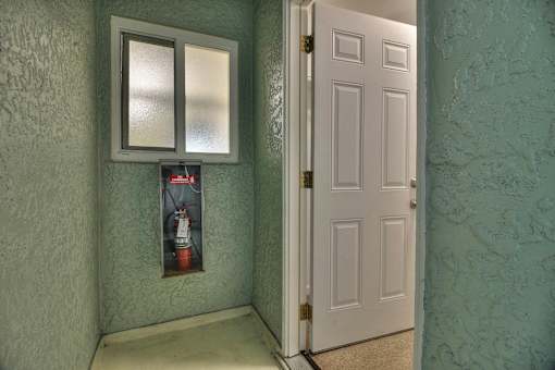 A white door is open to a hallway with a poster on the wall.
