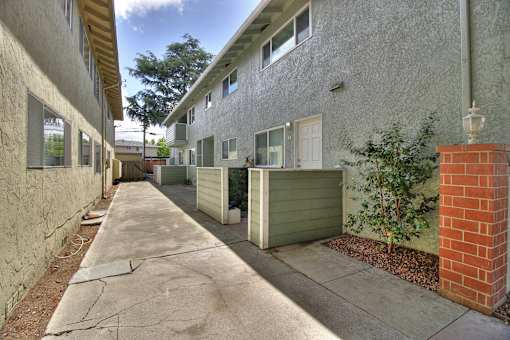 A long, narrow residential street with a sidewalk and garages.