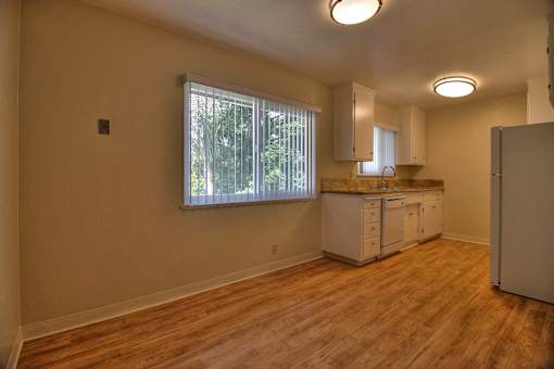 A kitchen area with wooden floors and white cabinets.