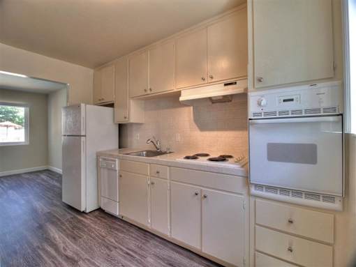 an empty kitchen with white cabinets and a refrigerator