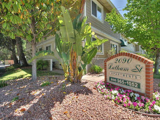 a sign in front of a house with a palm tree