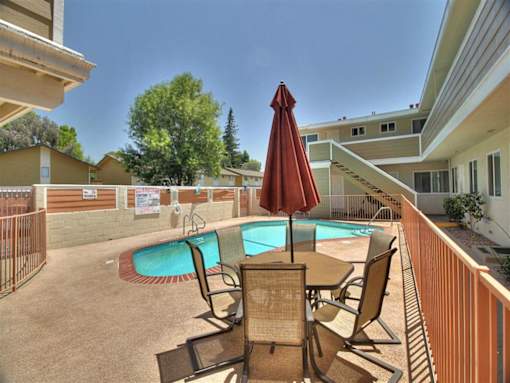 a patio with a pool and a table with chairs
