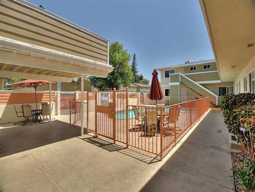a patio with an umbrella and chairs and a pool