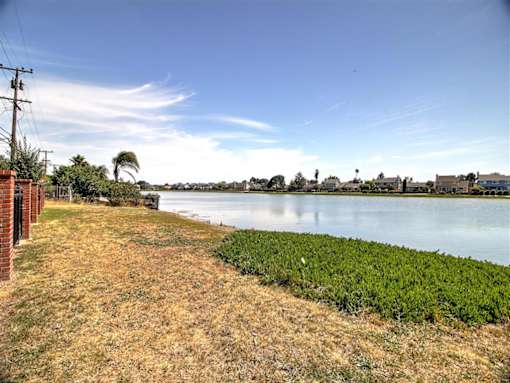 a body of water next to a grass field