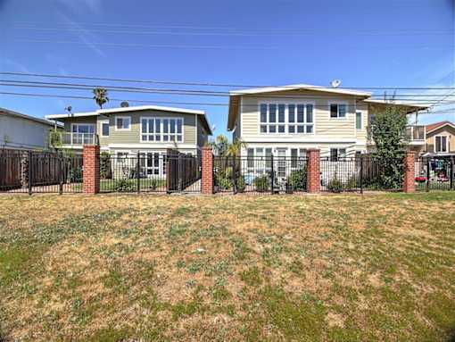 two houses behind a fence in front of a yard