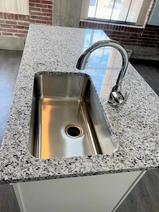 A stainless steel sink with a chrome faucet is installed in a granite countertop.