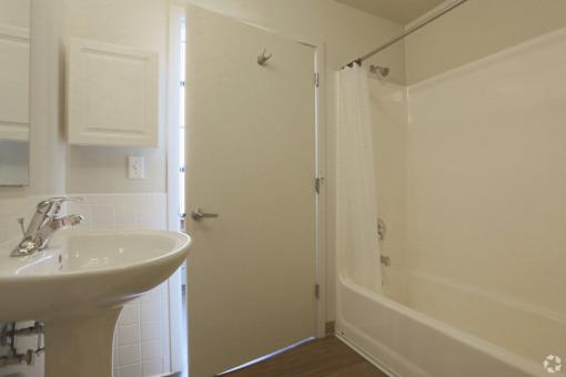 A white bathroom with a sink, mirror, and shower.