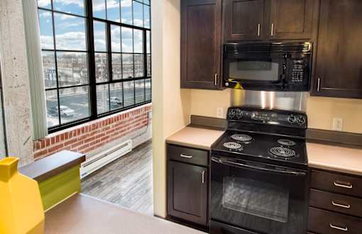 A kitchen with a black stove top oven and a black microwave above it.
