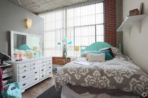 A bedroom with a bed, dresser, and window.