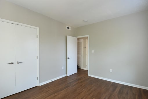 a bedroom with white walls and hardwood floors