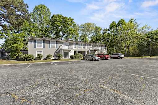 A parking lot with a building and cars parked in front.