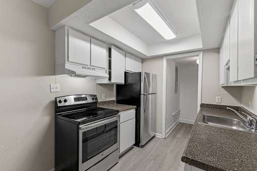 A kitchen with black appliances and white cabinets.
