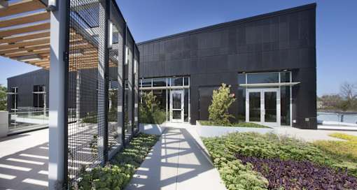 A modern building with a black facade and a garden in front.