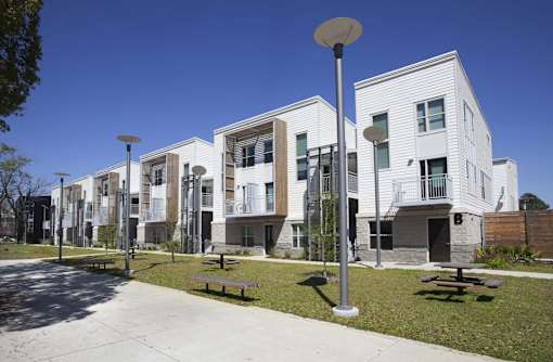 A row of modern white apartment buildings with balconies and a clear blue sky.