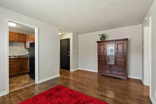 A room with a red rug and a wooden cabinet.
