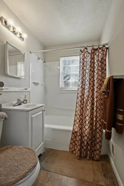 A small bathroom with a toilet, sink, and shower.