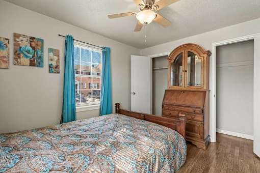 A bedroom with a bed, dresser, mirror, and ceiling fan.