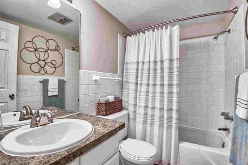 A bathroom with a white toilet, a sink, and a shower curtain.