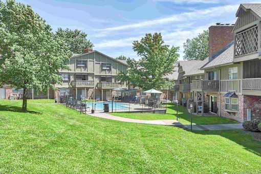 A sunny day at a residential apartment complex with a pool and green lawns.