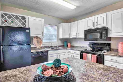 A kitchen with a black refrigerator and a decorative plate on the counter.